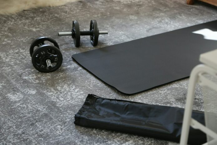 Photo by Giorgio Trovato a pair of dumbbells and a black mat on the floor