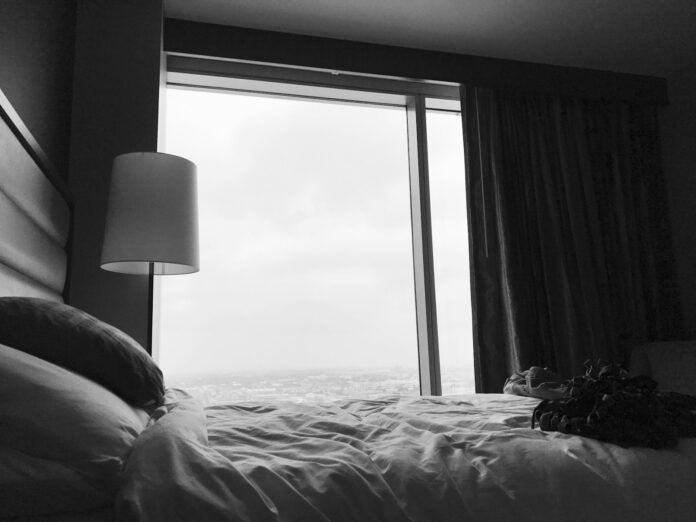 Photo by Shane McKnight grayscale photo of bed near white table lamp