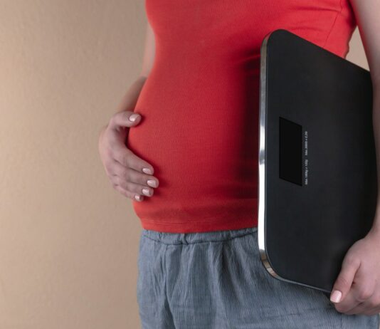 건강한 다이어트, 올바른 방법으로 몸매를 만들어보세요 pregnant woman touching her belly and carrying a digital bathrooms cale